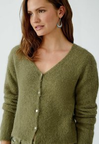 Olivgrüner Cardigan aus weichem, strukturiertem Stoff mit V-Ausschnitt, langen Ärmeln und silbernen Knöpfen an der Vorderseite.