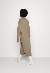 Lång, beige stickad klänning med avslappnad passform, sidospår och långa ärmar. Matchad med vita, kraftiga ankelboots.