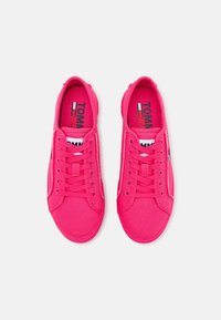 Zapatillas de lona rosa con cordones, puntera redonda, acentos blancos y logo en la plantilla. Parte superior texturizada y suela de goma.