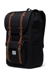 Schwarzer Canvas-Rucksack mit braunen Lederriemen und silbernem Metallzubehör, ausgestattet mit einem Klappenverschluss und einer Fronttasche.