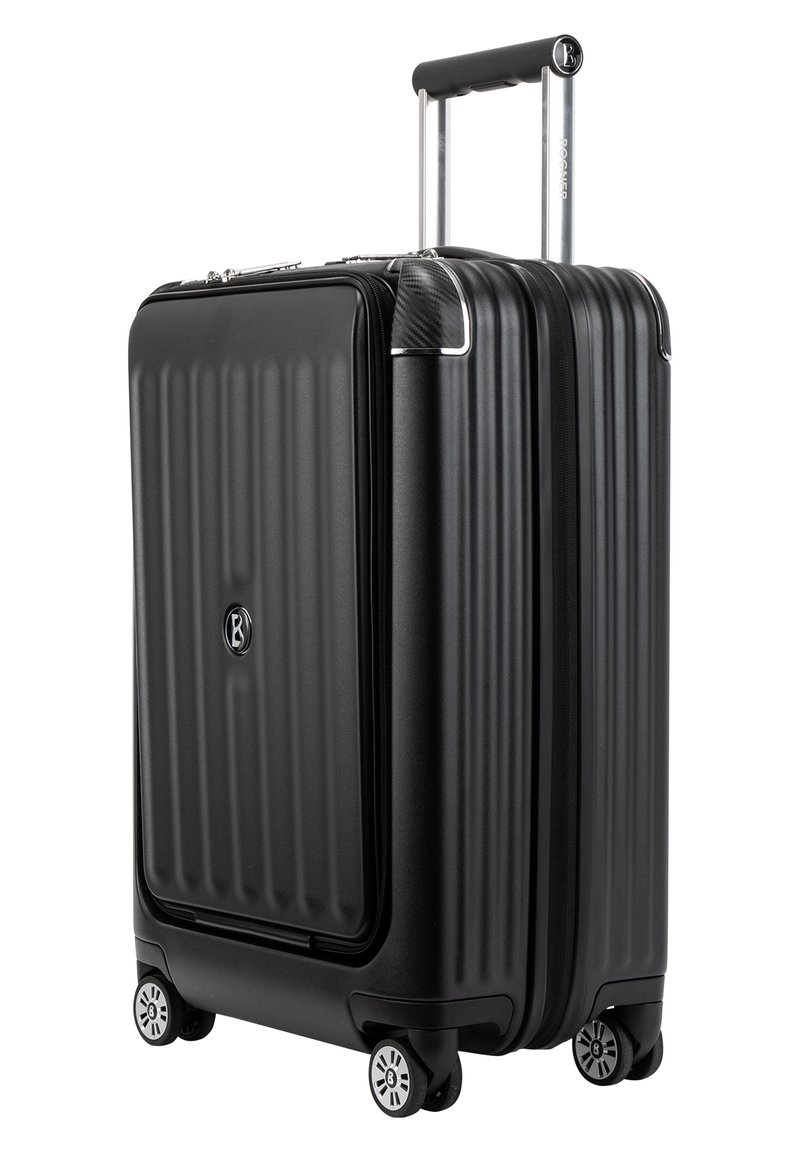 Schwarzer Hartschalenkoffer mit vertikalen Rillen, silbernem ausziehbarem Griff und vier Rädern. Verfügt über ein Schloss und eine strukturierte Oberfläche.