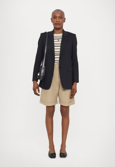 Blazer in navy, striped top, beige shorts with rolled cuffs, black flats, and a small black crossbody bag. Simple, tailored design.