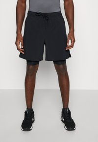 Black athletic shorts made from lightweight fabric, featuring an elastic waistband with drawstring, side pockets, and a subtle logo detail.