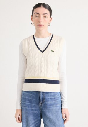 Gilet di cotone lavorato a maglia color crema con scollatura a V, strisce blu navy e gialle in vita, con un piccolo logo verde sul petto.