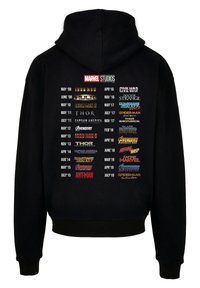 Black hooded sweatshirt featuring a printed list of Marvel Studios film titles and release dates on the back in various colors and fonts.