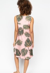 Mouwloze roze jurk met groen bladrandpatroon; zachte stof; ontspannen pasvorm; gebogen zoomlijn; rugplooidetail voor extra volume.