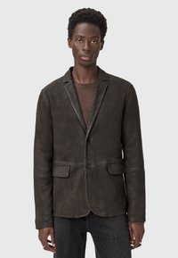 Blazer in pelle marrone scuro con due tasche anteriori, chiusura a un bottone e vestibilità su misura. La texture è liscia con una leggera lucentezza.