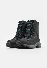 Svarte vanntette støvler med teksturert overflate, med teal snørebånd og detaljer, høy-topp design, tykke gummisåler og forsterkede tåbeskyttelser.