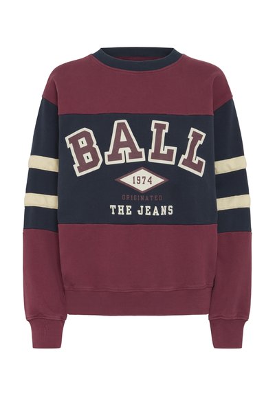 Bordo ja tumesinine sviiter, millel on kreemjad horzontaalsed triibud, ümar kaelus ja julge tekstigraafika, mis ütleb "BALL 1974 ORIGINATED THE JEANS."