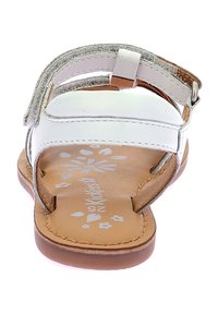 Sandalia blanca con suela marrón, tira plateada ajustable, parte superior de cuero suave, detalles florales en la plantilla y diseño de punta abierta.