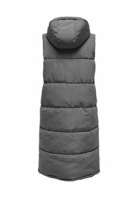 Gilet sans manches rembourré en gris, avec capuche. Il présente des sections matelassées horizontales et un ourlet arrière légèrement plus long. Texture lisse et mate.