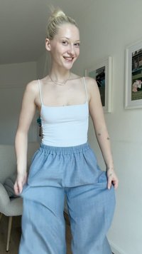 Hellblaue, locker sitzende Leinenhosen mit einem elastischen Bund, kombiniert mit einem enganliegenden weißen Tanktop. Angenehme Textur und schlichte Design.