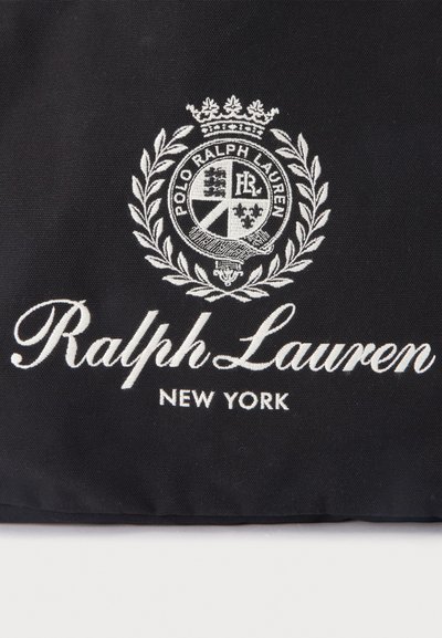Μαύρο ύφασμα με λευκό κεντημένο έμβλημα Ralph Lauren, στεφάνι δάφνης και κείμενο που γράφει Ralph Lauren New York.