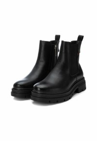 Botines de cuero negro con puntera redonda, paneles laterales elásticos y suela de goma con tacos. Presentan un cierre de cremallera en un lado para un acceso fácil.