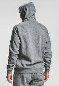 Šedá mikina s těsným střihem, vyrobená z měkkého materiálu, má kapuci, žebrované manžety a hladký povrch, zobrazená zezadu.