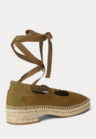 Επίπεδη εσπαντρίγια σε ελιά πράσινο χρώμα με πλεκτή σόλα από τζούτ και κορδέλες για τύλιγμα στον αστράγαλο, πάνω σε λευκό φόντο.