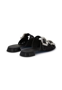 Black slide shoes featuring a textured upper, two prominent rhinestone-embellished buckles, and a low, chunky heel.