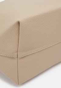 Gros plan d'un coin en cuir texturé beige avec des coutures visibles le long des bords des coutures.