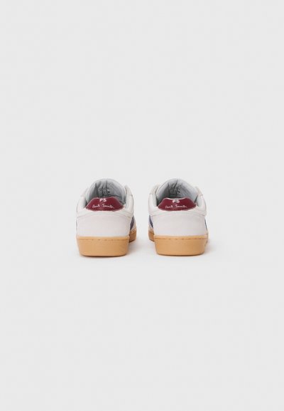 Hvite sneakers med grå og marineblå detaljer, gummisåle og "PS" logo på den røde hæltappen. Har en myk suede tekstur.