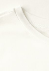 Hvid bomulds T-shirt stof med en glat tekstur, der har en rund halsudskæring og diskret ribbede detaljer ved kraven. Ingen synlige mønstre eller accenter.