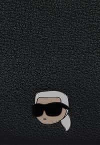 Suprafață din piele texturată neagră, cu un personaj de desene animate purtând ochelari de soare, în alb și negru. Design simplu, fără accente suplimentare.