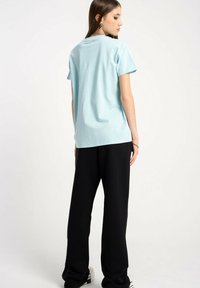 Jasnoniebieska bawełniana koszulka z krótkim rękawem, luźny krój, okrągły dekolt, w połączeniu z czarnymi spodniami o szerokich nogawkach.