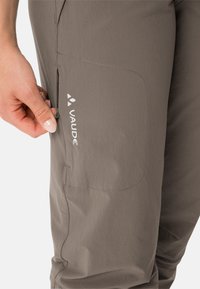 Pantaloni tecnici leggeri grigi con tasca laterale con zip e logo visibile. Tessuto liscio con vestibilità su misura.