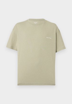 T-shirt beige a maniche corte con scollo rotondo e piccolo testo bianco "originals © 1990" sul petto a sinistra.