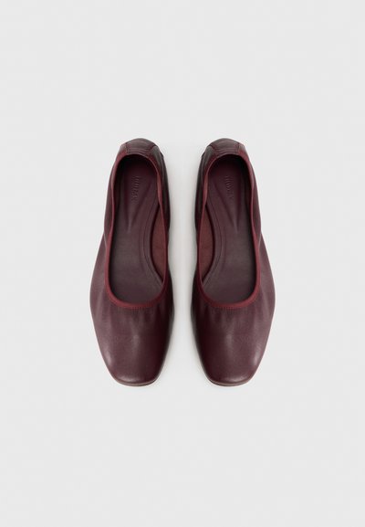 Ballerines en cuir bordeaux avec une finition lisse, bout rond et bord élastiqué autour de l'ouverture pour un maintien sécurisé.