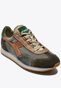 Zapatilla de deporte con cordones que presenta una mezcla de verde oliva, cuero marrón y ante gris, con una media suela blanca y suela de goma texturizada.