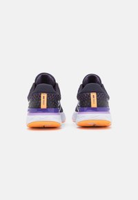 Zapatillas de correr negras y moradas con parte superior de malla, cuello acolchado y media suela blanca. Presentan acentos naranjas en el talón y la suela exterior.