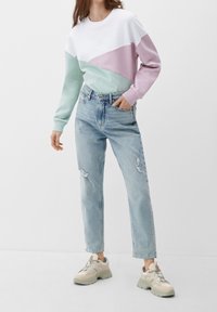 Mikina s barevnými bloky v bílé, mátově zelené a světle růžové barvě. Nošeno s světle modrými roztrhanými džíny a béžovými teniskami se šedými akcenty.