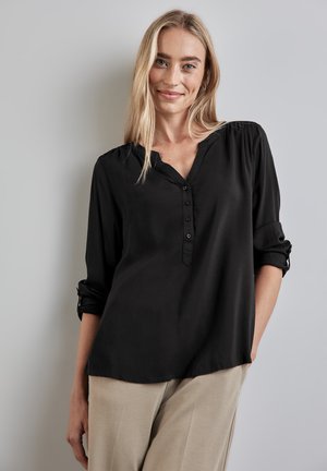 Blusa nera a maniche lunghe con scollo a V, apertura con bottoni e polsini arrotolati. Realizzata in un tessuto liscio e leggero.