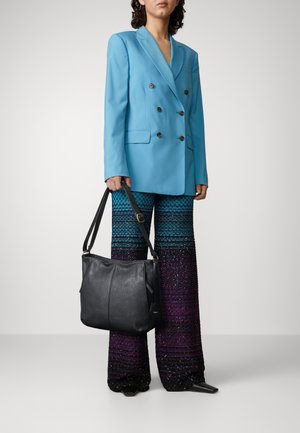 Vaaleansininen kaksoisnapitettu bleiseri, joka on yhdistetty paksuihin, monivärisiin neulottuihin liehuviin housuihin. Musta nahkainen olkalaukku, jossa on hihna.