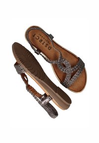 Zilveren gevlochten sandalen met een platte bruine zool. De bandjes hebben een gestructureerde afwerking en de voetbed is een glad, lichtbruin.