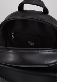 Černý syntetický batoh s oválným designem, vnitřní kapsou na zip a štítkem s logem "even & odd". Hladký povrch a minimalistický styl.