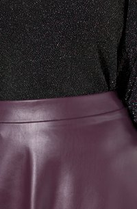 Haut en tissu pailleté noir au-dessus d'une jupe en cuir violet profond avec une texture lisse et une taille simple.