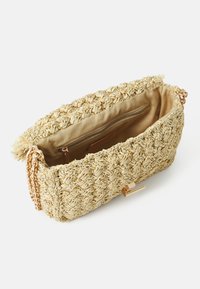 Πλεκτή τσάντα από καλάμι σε ανοιχτό μπεζ με υφή εξωτερική, χρυσή αλυσίδα και εσωτερική τσέπη με φερμουάρ. Ορατή λεπτομέρεια κλεισίματος με κούμπωμα.