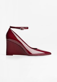 Burgundy patentti wedge-korkokenkä, jossa on teräväkärkinen muoto ja soljella varustettu nilkkaremmi. Tasainen pinta kiiltävällä viimeistelyllä.