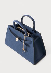 Top-handle handbag in dark blue suede with gold-tone hardware, featuring a bow accent, zipper closure, and a chain with a key charm.