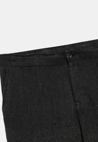 Pantalons en denim noir à coupe droite, dotés d'une fermeture par bouton et d'un tissu texturé, mettant en avant un design épuré et minimal.