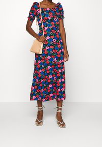 Květinové midi šaty v černé barvě se červenými, modrými a růžovými květinami. Nadýchané rukávy a čtvercový výstřih. Doplněno sandály na řemínky a béžovou kabelkou.