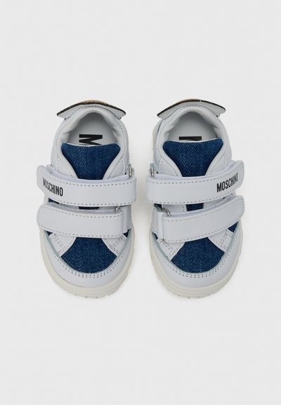 Λευκά αθλητικά παπούτσια με denim λεπτομέρεια, διαθέτουν δύο λουράκια με βέλκρο, στρογγυλεμένο σχήμα, υφή στην επιφάνεια και λογότυπο στο πλάι.