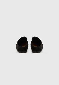 Sorte semsket loafers med rund tå, flat såle og ingen synlig maskinvare. Har en glatt tekstur og en slip-on design.