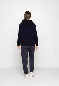 Marinblå hoodie med lång ärm, ribbad mudd och nederkant. Matchad med mörkgrå sweatpants. Vita sneakers med färgade detaljer.