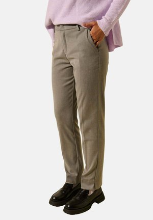 Pantalons taillés gris clair avec une coupe ajustée, présentant un design à l'avant plat et des poches latérales, complétés par des chaussures noires.
