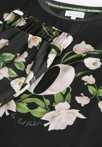 Černý top se květinovým vzorem s růžovými a bílými květinami, nabíranou texturou na výstřihu a štítkem "by Ted Baker".