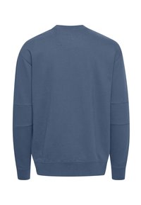 Sweat-shirt col rond à manches longues bleu sourd, avec poignets et ourlet côtelés, et des détails de coutures minimalistes sur les manches et le haut du dos.
