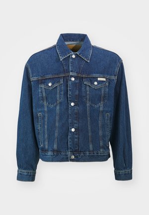Chaqueta de mezclilla en azul oscuro con cuello clásico, bolsillos frontales y botones plateados. Presenta un diseño estructurado y detalles de costura visibles.
