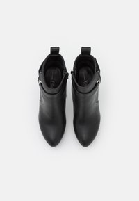 Czarne skórzane botki za kostkę z ostrymi noskami, suwakiem po boku i pętelką na obcasie. Gładka tekstura i elegancki design.